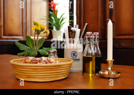 Il Schoberwirt è il più antico guest-house a Unteren Alm, Monaco di Baviera. Tavolo con pretzel cestello, oli, candela e fiori Foto Stock