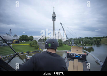 Un guidatore di skateboard treni sulla grande rampa sul lago olimpico per lo skateboard Big Air finale al X-Games Monaco di Baviera. Sullo sfondo la torre olimpica. Foto Stock