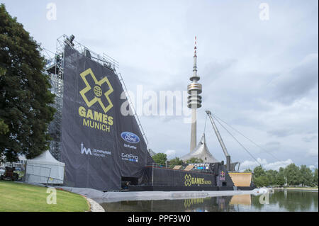 Un guidatore di skateboard treni sulla grande rampa sul lago olimpico per lo skateboard Big Air finale al X-Games Monaco di Baviera. Sullo sfondo la torre olimpica. Foto Stock