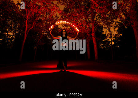 Strega a giocare con le luci come fuoco nella foresta durante il periodo di halloween Foto Stock