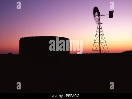 Il mulino a vento e acqua del serbatoio al crepuscolo in Australian Outback, Western Australia | Utilizzo di tutto il mondo Foto Stock