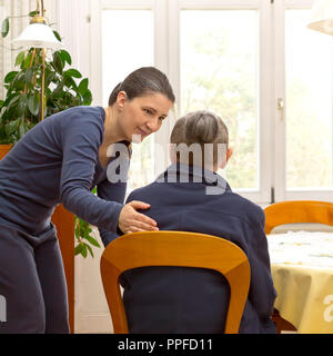 Vista posteriore di un senior donna seduta a casa a parlare con una giovane donna da un domestico care service che sta aiutando il suo durante la giornata, lo spazio di testo Foto Stock