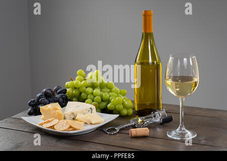 Bicchiere di vino bianco con bottiglia di vino, formaggio e uva Foto Stock