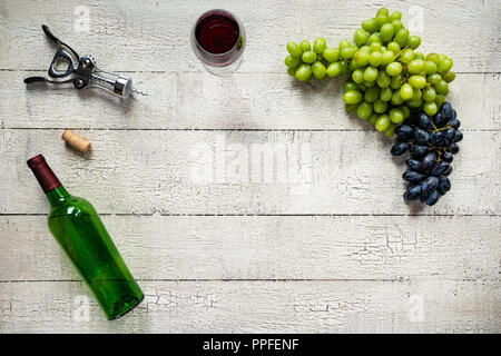 Vino rosso con uve su un weathered, peeling bianco tavola di legno Foto Stock