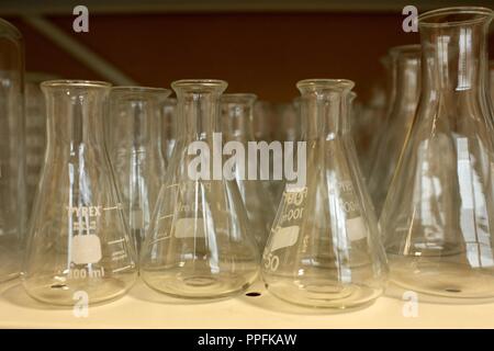 Matraccio di Erlenmeyer cilindri di vetro su un ripiano in un completo scuola laboratorio di chimica Foto Stock