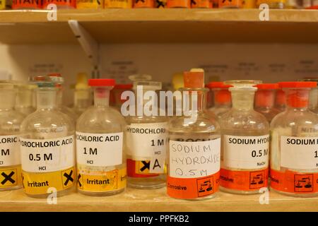 Varie bottiglie di sostanze chimiche inclusi idrossido di sodio in una scuola laboratorio di chimica Foto Stock