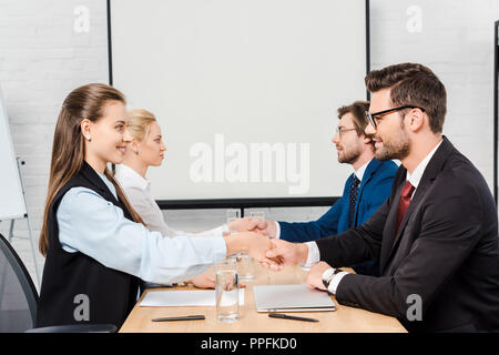 Due squadre di uomini di affari che si stringono la mano durante la riunione in ufficio moderno Foto Stock