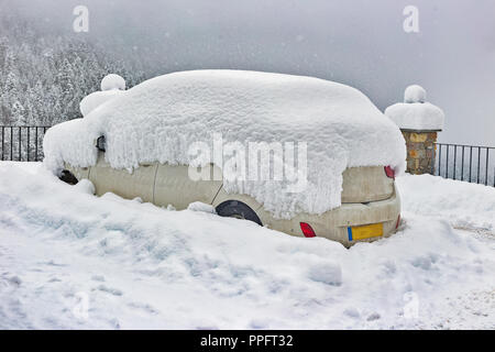 Le vetture in parcheggio nella neve. Nuvoloso Giorno d'inverno, di neve, cumuli di neve sui tetti delle vetture. Vicino a tracce di pneumatici sulla neve Foto Stock