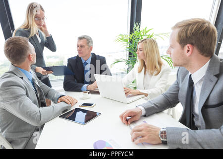 Un gruppo di persone di affari a discutere di un documenti finanziari alla riunione Foto Stock