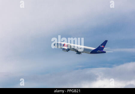 FedEx cargo aereo decollare ad Anchorage in Alaska in un cielo blu con nuvole bianche Foto Stock