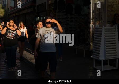 Domenica pomeriggio le persone camminano giù Ifaistou street nella zona di Monastiraki, contro il sole di setting. Atene. Foto Stock