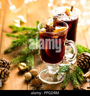 Natale rimuginassero vino rosso con le spezie e le arance in un rustico in legno tavolo. Tradizionale bevanda calda a Natale Foto Stock