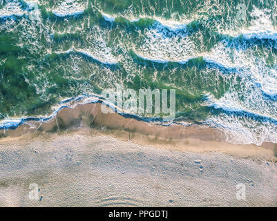 Vista aerea di schiantarsi in onda ocean con una calda luce del tramonto. Wave si infrangono sulla barriera corallina. Vista superiore Foto Stock