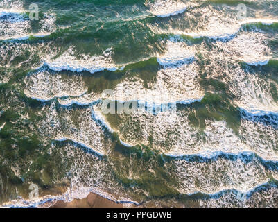 Vista aerea di schiantarsi in onda ocean con una calda luce del tramonto. Vista superiore Foto Stock