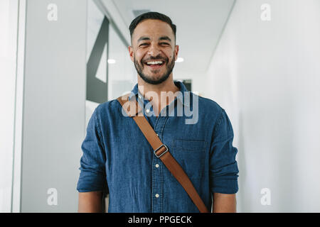Ritratto di felice giovane nel corridoio di office. Uomo in casuals in ufficio corridoio. Foto Stock