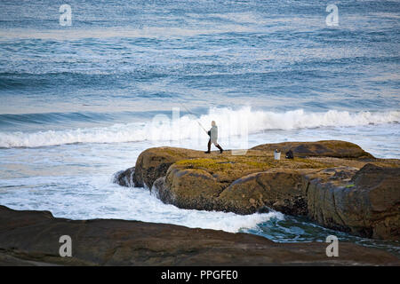 Un solitario pescatore surf getta nell'Oceano Pacifico in una nebbiosa mattina vicino a Yachats, Oregon, in tarda estate. Foto Stock