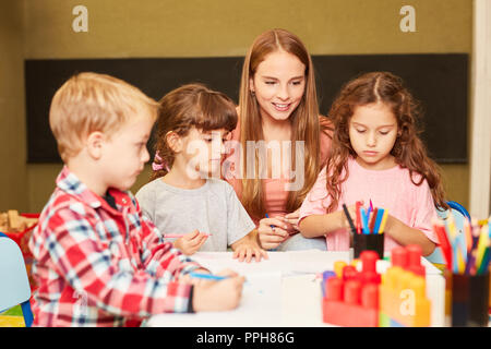 La donna come un insegnante e i bambini nella classe di arte nella scuola materna o asilo nido Foto Stock