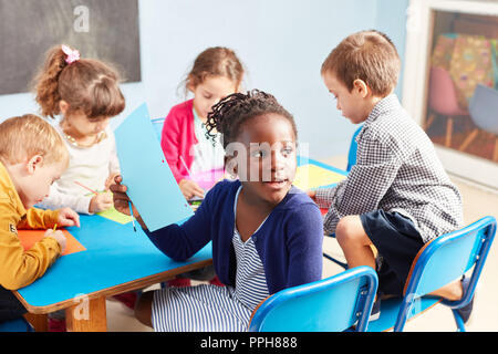 Un gruppo di bambini mentre la pittura insieme nella classe di disegno in asilo nido o alla scuola materna Foto Stock