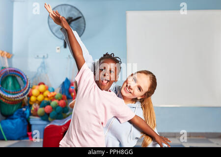 Ragazza e sport insegnante fare ginnastica e divertimento nel pre-scuola di educazione fisica Foto Stock