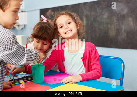 Felice ragazza in pittura creativa classe nella scuola materna insieme con gli amici Foto Stock