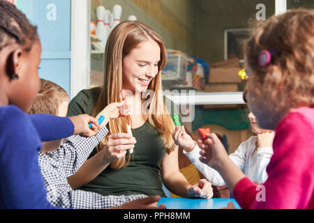 Accompagnatore e giocare i bambini con argilla in vivaio o asilo nido Foto Stock