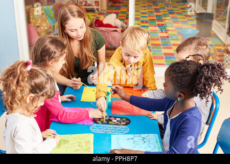 Gruppo di bambini di vernici con colori ad acqua nella classe di pittura nella scuola materna insieme con gli insegnanti Foto Stock