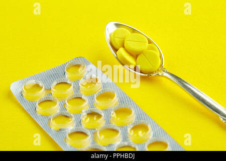 Cucchiaio con pillole e un pacchetto vuoto di compresse. Foto Stock