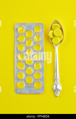 Cucchiaio con pillole e un pacchetto vuoto di compresse. Foto Stock