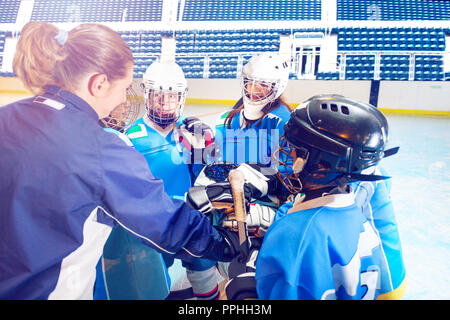 Allenatore e giocatori di hockey di unire le vostre mani in huddle Foto Stock