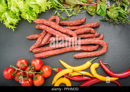 Sfondo di cibo. Snack stick salsicce su un tavolo di legno Foto Stock