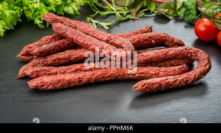 Sfondo di cibo. Snack stick salsicce su un tavolo di legno Foto Stock