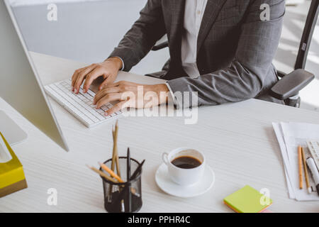 Immagine ritagliata di imprenditore digitando sulla tastiera del computer in ufficio Foto Stock