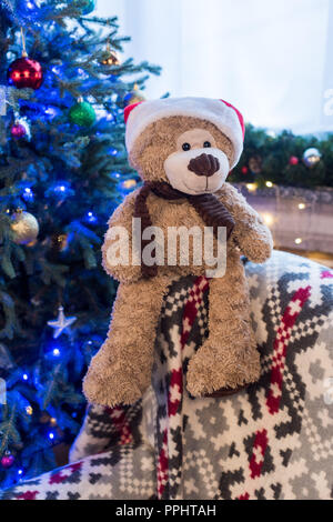 Vista ravvicinata di Teddy bear in santa hat e bellissimo albero di Natale decorato dietro Foto Stock