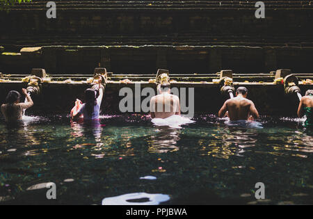 Persone in preghiera per le benedizioni di balneazione dall'acqua santa a tempio a Bali. Foto Stock