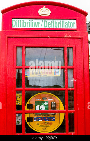 Telefono rosso box convertito in casa del defibrillatore di emergenza in caso di attacchi di cuore , Conwy Galles del Nord village REGNO UNITO Foto Stock