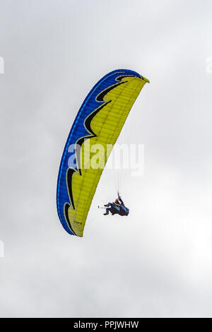 Il parapendio in tandem con giallo blu parapendio, cielo grigio Foto Stock