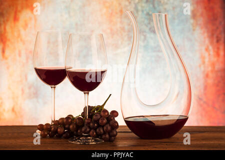Decanter in vetro con vino rosso e uva Foto Stock