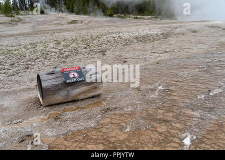 Un log con un cartello di avviso avverte i turisti ed i visitatori di restare al di fuori della aree termali nel parco nazionale di Yellowstone. Hot Springs raggiungere alte temperatur Foto Stock