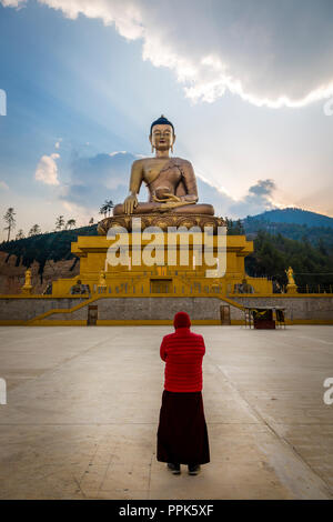 Una persona in preghiera presso la statua di Dordenma Big Buddha vicino a Thimpu nel regno himalayano del Bhutan Foto Stock