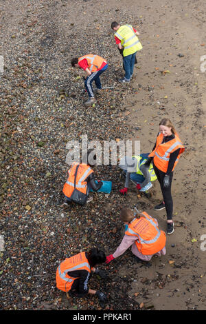 Un gruppo di volontari od pulizia spiaggia la raccolta di rifiuti e immondizie sulle rive o riva del fiume Tamigi nel centro di Londra. aiutanti ambientale. Foto Stock