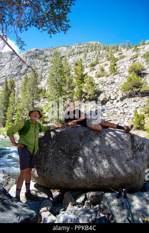 Un padre e figlio rilassarsi presso il famoso John Muir Rock, lungo il John Muir Trail. Lungo evoluzione Creek, Sequoia-Kings Canyon deserto; Kings Canyon N Foto Stock
