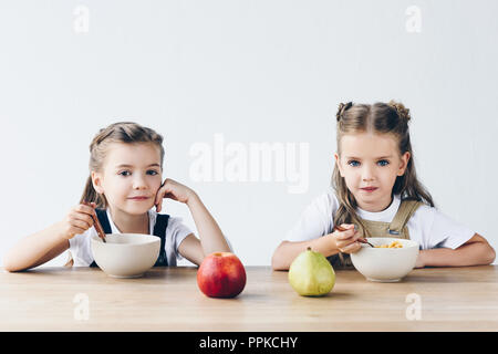 Adorabili e sorridente studentesse mangiare cereali con frutta a colazione isolato su bianco Foto Stock