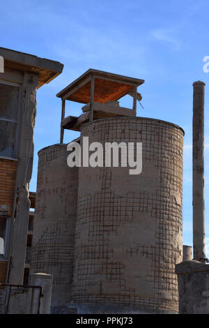 Abbandonato il vecchio stabilimento area con torri e camini, la vecchia fabbrica abbandonata in Sardegna, perso il posto facciata di fabbrica Foto Stock