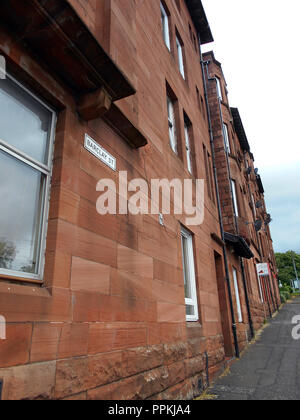 Una strada di pietra arenaria rossa tenements che sono un alloggiamento popolare scelta per case in Glasgow. Foto Stock