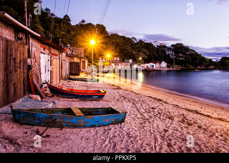 Barche sulla sabbia di fronte boathouses in una comunità di pescatori a Tapera spiaggia al tramonto. Florianopolis, Santa Catarina, Brasile. Foto Stock