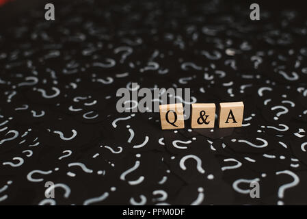 Alfabeto di legno piastrelle con Q&una lettera su carta nera con un punto interrogativo. Concetto di punto di domanda e risposta Q&A assistenza online Foto Stock