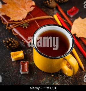 Smalto giallo tazze di tè, acquerelli in cuvette, matite colorate, autunno foglie di acero e dossi su uno sfondo marrone Foto Stock