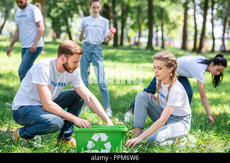 I giovani volontari di pulizia con prato verde casella di riciclaggio Foto Stock