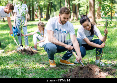 I giovani volontari l'impianto di nuovi alberi in posizione di parcheggio Foto Stock