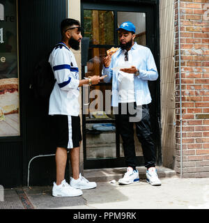 La città di New York, Stati Uniti d'America - 22 Giugno 2018: un paio di amici arabi sono a mangiare la pizza da un famoso italian street food nel Greenwich Village Foto Stock